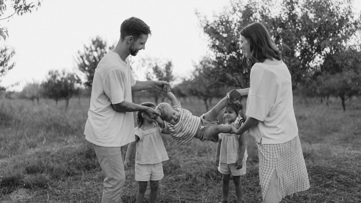 Family playing with child in grassy field