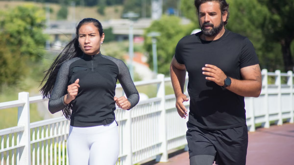 Active couple jogging outdoors on a sunny day, promoting fitness and healthy lifestyle.